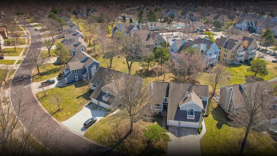 Charming suburban neighborhood aerial view showcasing spacious homes with lush green lawns and tree-lined streets in a serene community setting.