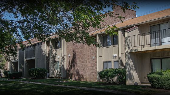 Charming residential complex with modern brick and wood exterior, featuring private balconies and lush landscaping.