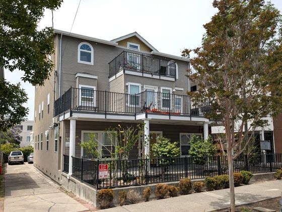 Charming multi-story apartment building with spacious balconies and a lush garden, offering modern urban living.
