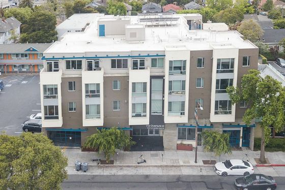 Modern urban apartment building with sleek design, large windows, and lush greenery, offering a vibrant city living experience.