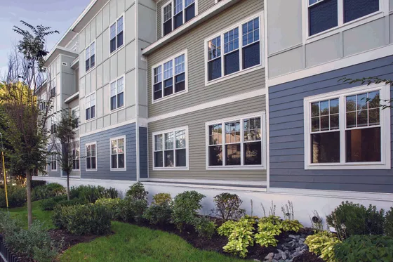 Charming apartment building with modern architecture and vibrant landscaping, featuring large windows and stylish exterior design.