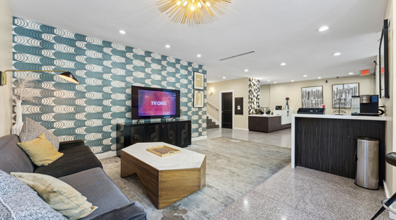 Modern living space with sleek decor, featuring a stylish patterned accent wall, comfortable seating, and a large flat-screen TV. Ideal for relaxation and entertainment.