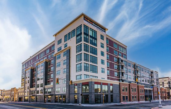 Modern apartment building with sleek architecture and large windows, featuring vibrant exterior colors under a clear blue sky.