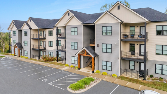 Modern apartment complex with stylish architecture, featuring spacious balconies and ample parking, surrounded by lush greenery.