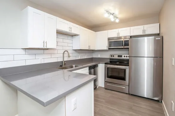 Modern kitchen with sleek stainless steel appliances, pristine white cabinetry, and elegant subway tile backsplash.