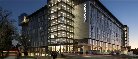 Modern apartment building with striking glass architecture illuminated at dusk, highlighting a vibrant urban lifestyle.