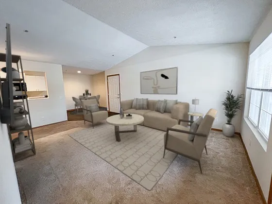 Bright and spacious living room with modern furnishings, including a comfortable sofa, stylish armchairs, and a large window allowing ample natural light.