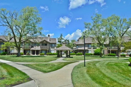Charming residential complex with lush landscaping and scenic pathways under a vivid blue sky.