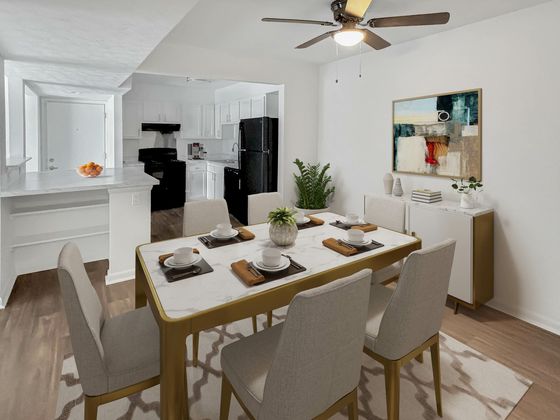 Contemporary dining area with a chic marble table set, adjacent to a modern kitchen featuring sleek black appliances and elegant decor.