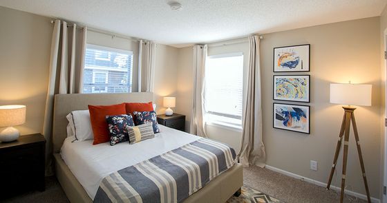 Bright and cozy bedroom featuring elegant bedding, stylish wall art, and abundant natural light.
