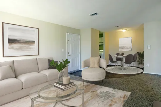Inviting living room with chic beige sofa, modern glass coffee table, and cozy armchair, offering a seamless flow to the stylish dining area.