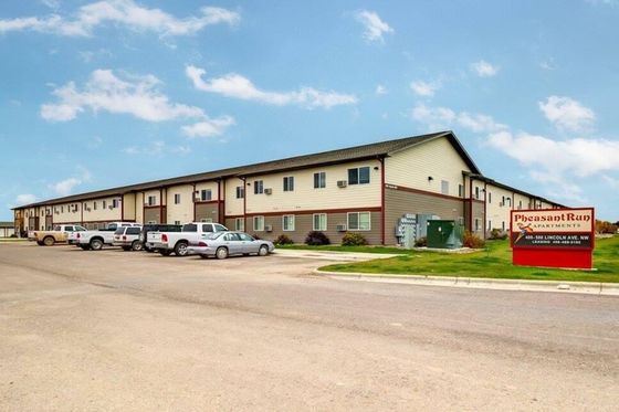 Charming Pheasant Run Apartments featuring a modern two-story building with ample parking and lush greenery, perfect for comfortable living.