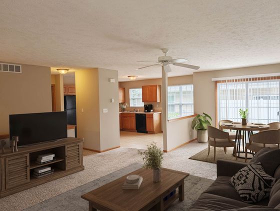 Bright and inviting open-concept living room with plush seating, a dining area, and a modern kitchen with wooden cabinetry, perfect for entertaining.