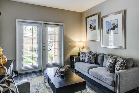 Chic and cozy living room with elegant decor, featuring a comfortable gray sofa, stylish abstract art, and bright natural light from large French doors.