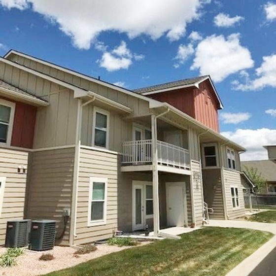Charming two-story apartment building with a rustic design, highlighting cozy balconies under a clear blue sky.