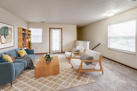 Charming living room featuring a cozy blue sofa, elegant armchairs, and natural light streaming in through large windows.
