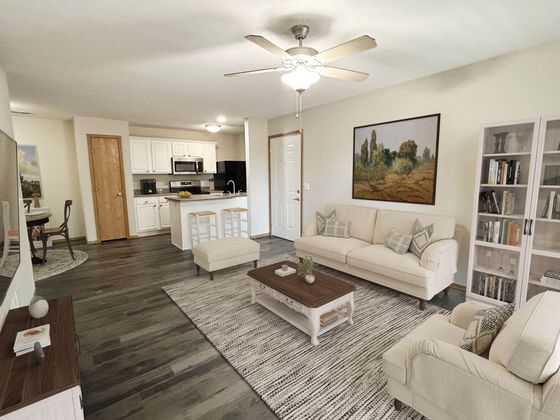 Inviting open-concept living room with elegant furniture, cozy seating, and a modern kitchen equipped with white cabinetry and stainless steel appliances.