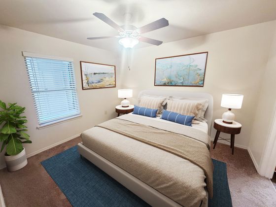Inviting bedroom with elegant decor, featuring a plush bed, stylish nightstands with modern lamps, and vibrant artworks, complemented by soft natural light and a ceiling fan.