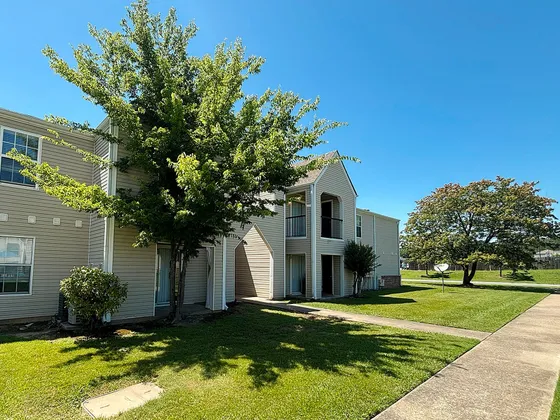 Charming apartment complex exterior with a lush green lawn and inviting pathways, perfect for a serene living environment.