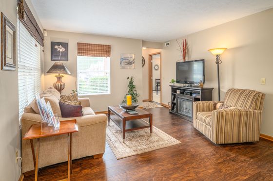 Inviting living room with cozy sofas, stylish floor lamp, and modern entertainment center, highlighted by warm wooden flooring and bright natural light.