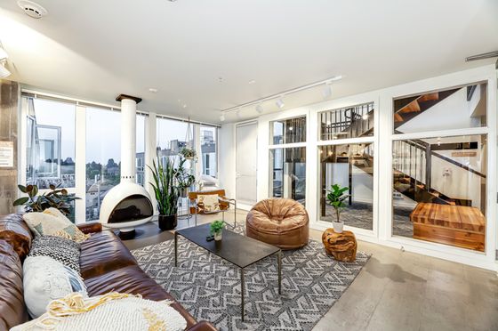 Modern living room with panoramic city views, sleek white fireplace, and cozy seating arrangement.