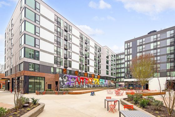 Modern apartment complex featuring vibrant street art and welcoming outdoor seating area.