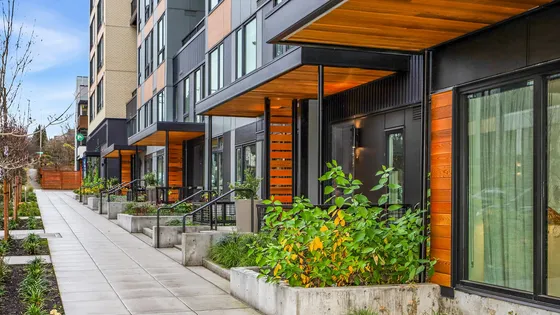 Modern city apartment exterior with sleek architecture, lush landscaping, and inviting walkways.