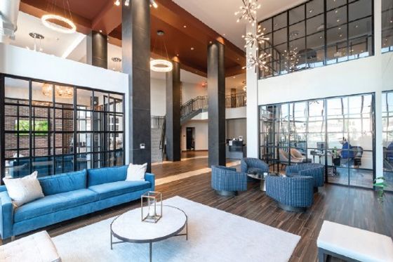 Luxurious modern lobby with high ceilings, stylish blue sofa, elegant lighting, and contemporary decor.