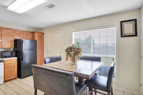 Bright and inviting kitchen with elegant wooden cabinetry, modern appliances, and a chic marble dining table set against a sunlit window.