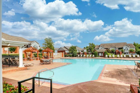Inviting outdoor pool area featuring elegant wooden pergolas, lounge chairs, and a sunny patio, perfect for relaxation and recreation.