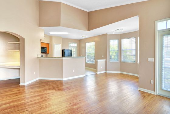 Bright and airy living area with elegant hardwood floors and open kitchen design, perfect for modern living.