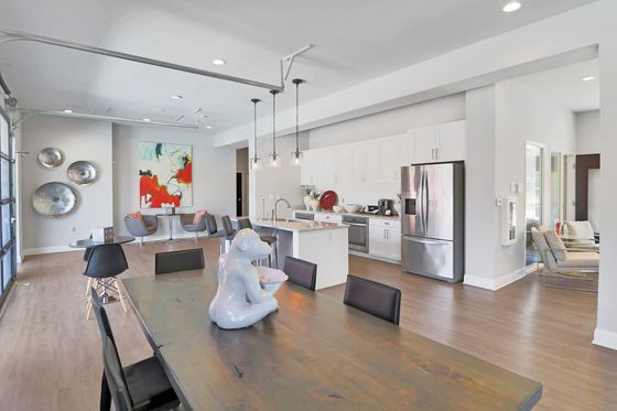 Modern open-concept apartment featuring a sleek kitchen, stylish dining area, and vibrant artwork complementing the bright, airy space.