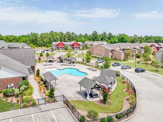 Inviting apartment complex with landscaped gardens, a sparkling swimming pool, and cozy gazebos, perfect for relaxation and leisure.