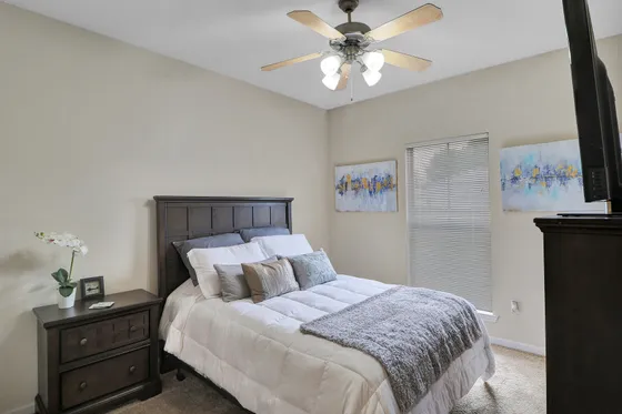 Inviting bedroom with elegant wooden furniture, plush bedding, and soothing artwork, enhanced by natural light from a large window.