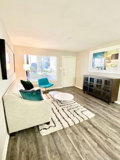 Bright and inviting living room with a modern sofa, stylish accent chair, and elegant flooring, perfect for relaxation.
