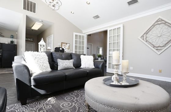 Chic living room with a sleek black leather sofa, elegant decor, and bright natural light enhancing the modern ambiance.
