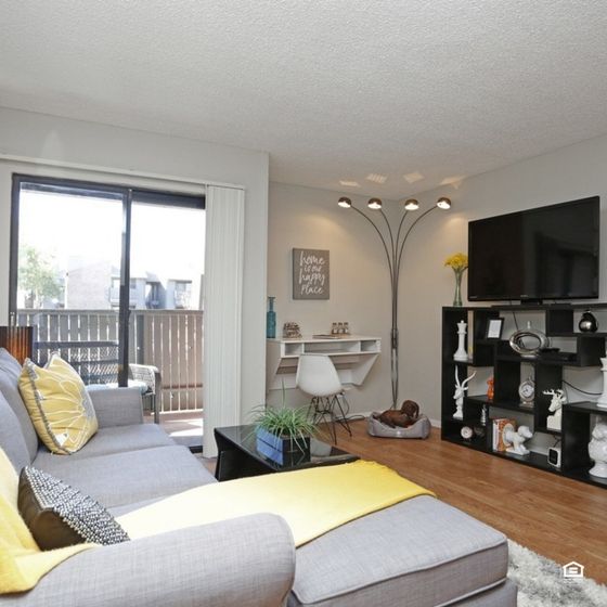 Inviting living room with elegant decor, featuring a sleek gray sofa, stylish modern shelving, and floor-to-ceiling windows opening to a private balcony.