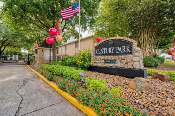 Welcoming entry at Century Park with vibrant landscaping, festive balloons, and a graceful American flag waving, setting a charming tone for this attractive community.