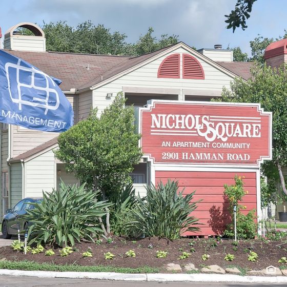 Welcoming entrance to Nichols Square Apartment Community with lush landscaping and a vibrant sign at 2901 Hamman Road.