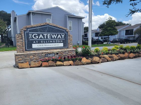 Inviting entrance to The Gateway at Ellington with charming stone sign and vibrant landscaping.