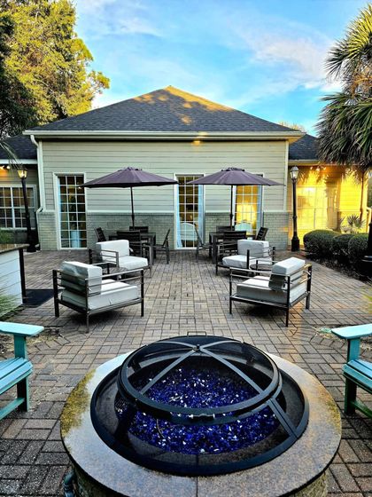 Charming outdoor patio with cozy seating, stylish umbrellas, and a decorative fire pit, set against a backdrop of lush greenery.