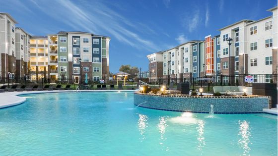 Chic apartment complex featuring modern architecture with inviting, illuminated outdoor pool and spacious patios.