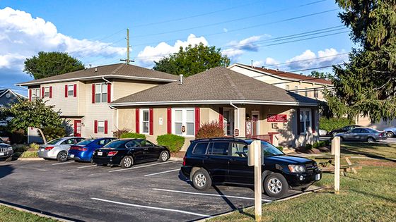 Charming apartment building with a welcoming exterior, surrounded by lush greenery and convenient parking spaces.