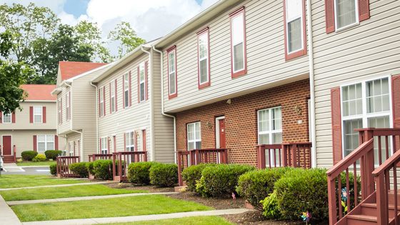 Charming apartment complex with elegant red-brick accents, lush landscaping, and inviting front porches.