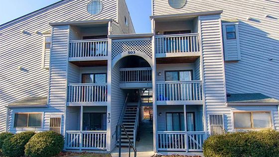 Charming apartment building with inviting balconies, nestled in a serene and sunny setting.