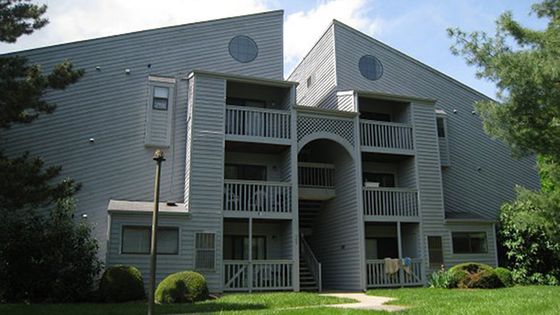 Charming multi-story apartment building with distinct architecture, featuring private balconies and surrounded by lush greenery.