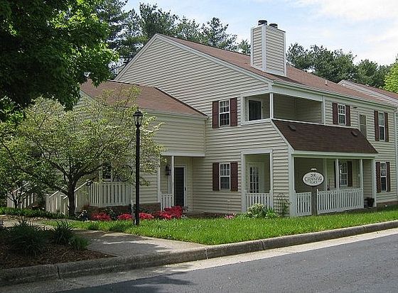 Charming suburban townhouse with elegant siding, lush landscaping, and inviting front porch, perfect for family living.