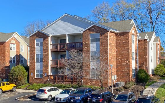 Charming brick apartment building with spacious balconies and ample parking, set in a vibrant, sunny neighborhood.