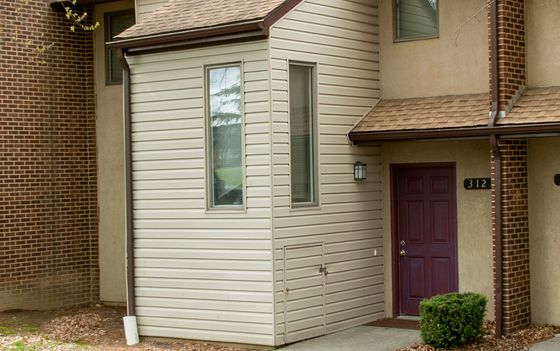 Charming townhouse exterior with brick and siding design, featuring a welcoming entryway and lush landscaping.