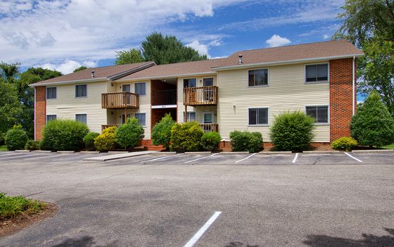 Charming apartment building with lush landscaping and ample parking, highlighting a serene residential environment.